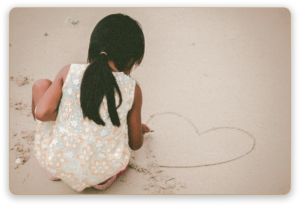 girl making a heart in the sand